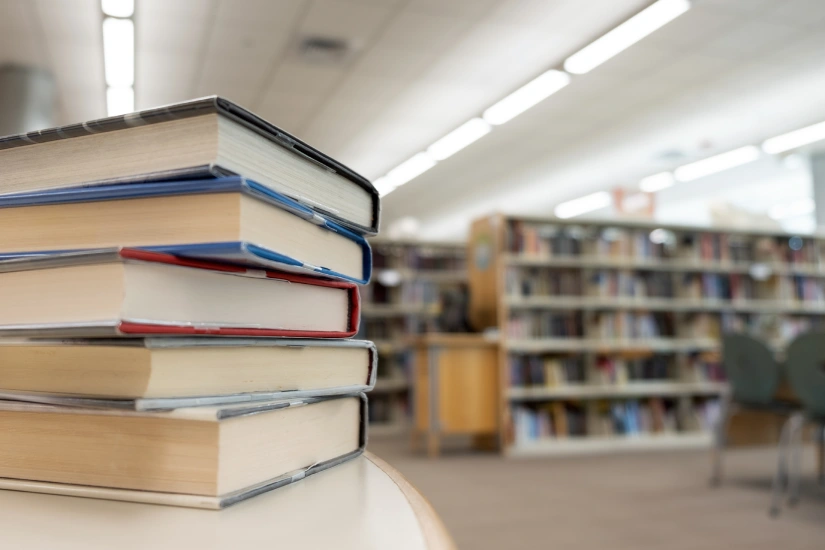 Une pile de livres avec la bibliothèque en fond